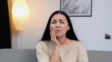 Genç kadına evde diş ağrısı veya dişlerde dişlerle ilgili hastalık nedeniyle ağız acı ifadesi ile el ile dokunmak. Diş hekimi kavramı.