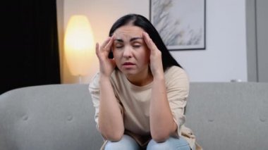 Kanepede başı ağrıyan bir kadın.