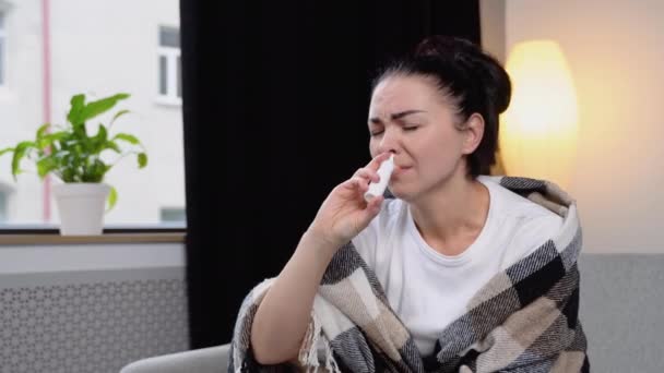 Young Woman Wrapped Blanket Sprays Nasal Spray While Sitting Sofa — Stock Video