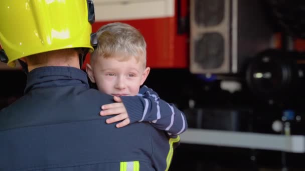 Хоробрий Пожежник Уніформі Тримає Маленького Врятованого Хлопчика Стоїть Тлі Пожежного — стокове відео