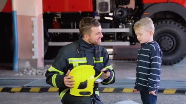 Μικρό Αγόρι Πυροσβέστη Προστατευτική Στολή Στον Πυροσβεστικό Σταθμό — Αρχείο Βίντεο