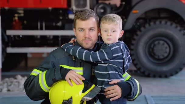 Porträtt Brandman Med Söt Pojke Armar Begreppet Rädda Liv Brandsäkerhet — Stockvideo
