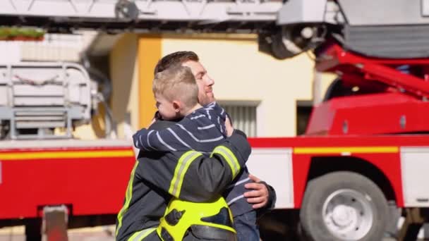 Modig Brandman Uniform Kramar Liten Pojke Med Leksak Mot Brandbil — Stockvideo