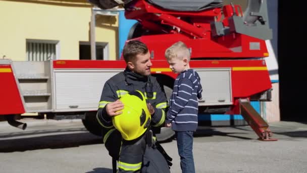 Kleiner Junge Mit Feuerwehrmann Schutzuniform Feuerwehrhaus — Stockvideo