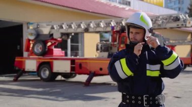 Donanımlı kostümlü yakışıklı itfaiyecinin portresi bir kask takıyor ve kameraya bakıyor..