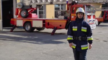 Kasklı beyaz itfaiyeci kameraya doğru geliyor ve gülümsüyor..
