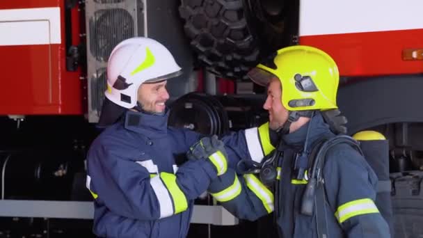 Dva Hasiči Ochranných Oděvech Helmách Hasičským Strojem Přátelský Stisk Ruky — Stock video