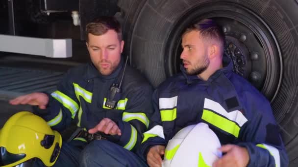 Zwei Müde Feuerwehrleute Sitzen Nach Einem Brand Der Nähe Eines — Stockvideo