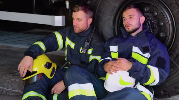 Δύο Κουρασμένοι Πυροσβέστες Κάθονται Δίπλα Ένα Πυροσβεστικό Όχημα Μετά Από — Αρχείο Βίντεο