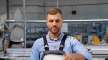 Teçhizatlı kostüm giymiş, kaskını çıkarıp kameraya bakan yakışıklı işçinin portresi.