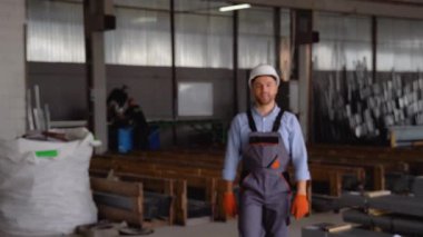 Güvenlik üniforması giyen profesyonel mühendis kameraya doğru geliyor ve gülümsüyor.