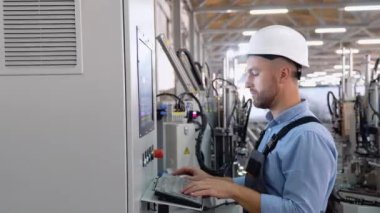 Fabrikada güvenlik üniforması ve kask giyen endüstriyel işçiler. Makine operatörü.