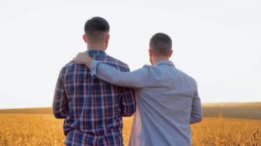 Gün batımının arka planında sarılan iki genç adam, ufku dört gözle bekliyorlar..