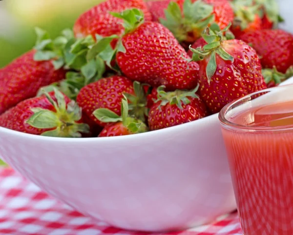 Jordgubbsjuice och full skål med jordgubbar — Stockfoto