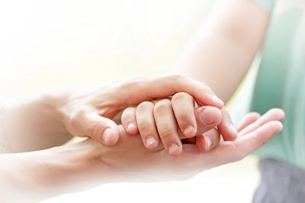 Mamma håller en hand på hennes son — Stockfoto