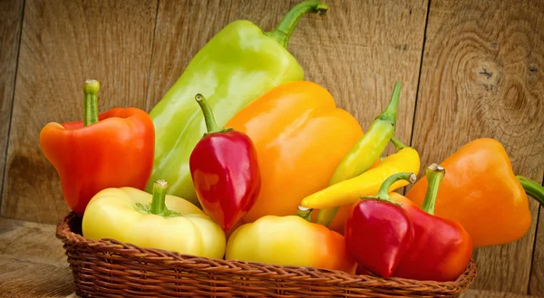 Organic peppers in wicker basket — Stock Photo, Image