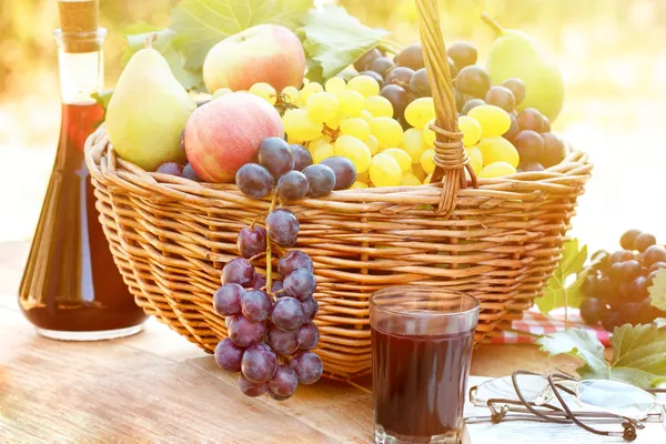 Druiven in rieten mand en rode wijn — Stockfoto