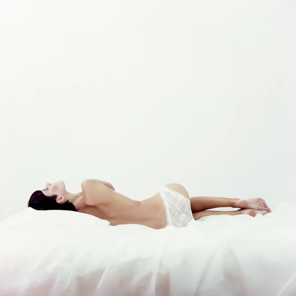 Retrato de moda de una hermosa chica dormida en cama blanca Imagen de archivo