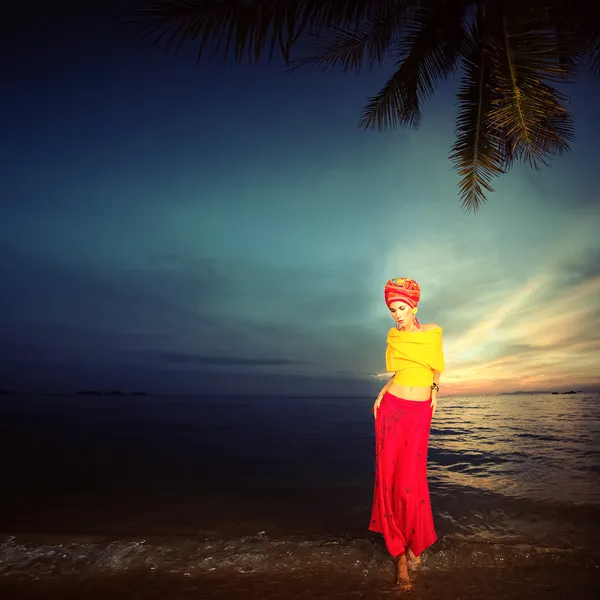 Smyslná dívka v orientálním stylu na pláži při západu slunce — Stock fotografie