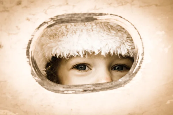 Child looking through hole — Stock Photo, Image