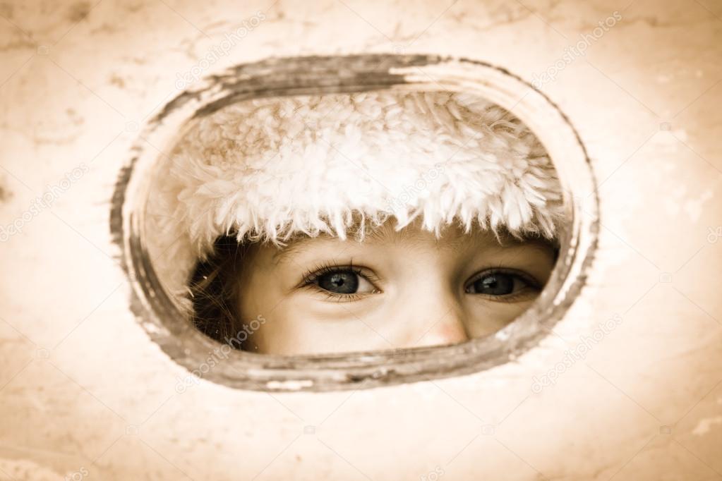 Child looking through hole