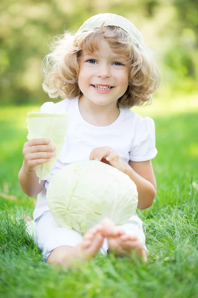 Criança com legumes no parque da primavera — Fotografia de Stock