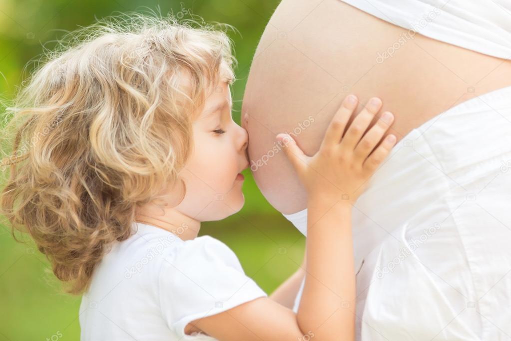 Child kissing belly of pregnant woman