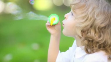 spring Park'ta sabun köpüğü üfleme mutlu bir çocuk. ağır çekim