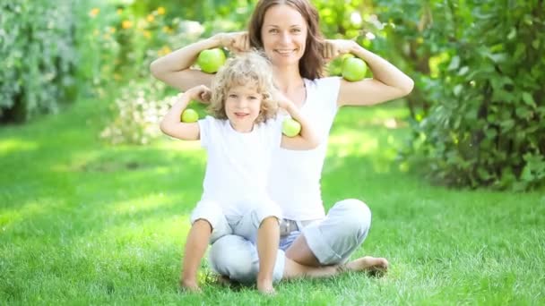 Familia feliz sentado en la hierba verde y jugar con frutas y verduras en el parque de primavera. concepto de alimentación saludable — Vídeo de stock