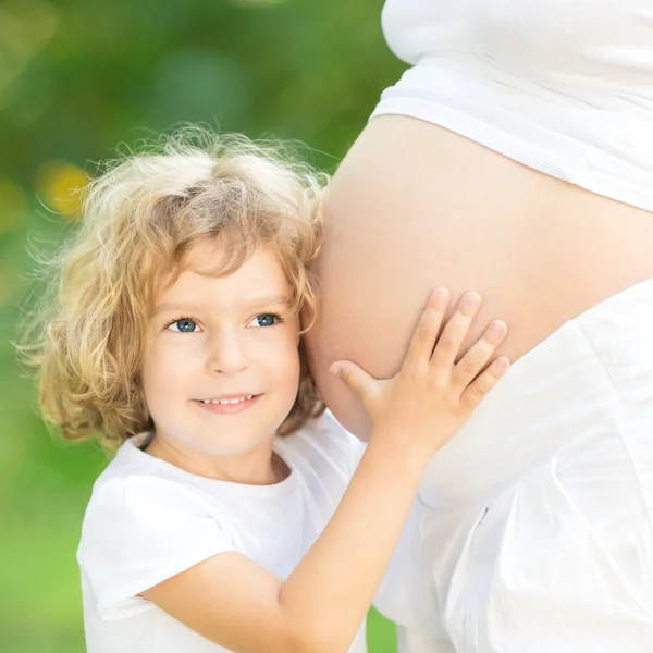 Niño sosteniendo el vientre de la madre embarazada Imagen de stock