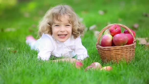 Gelukkig kind met rode appels in herfst park — Stockvideo