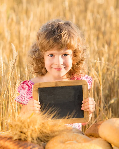 Glückliches Kind mit Brot auf dem Feld — Stockfoto