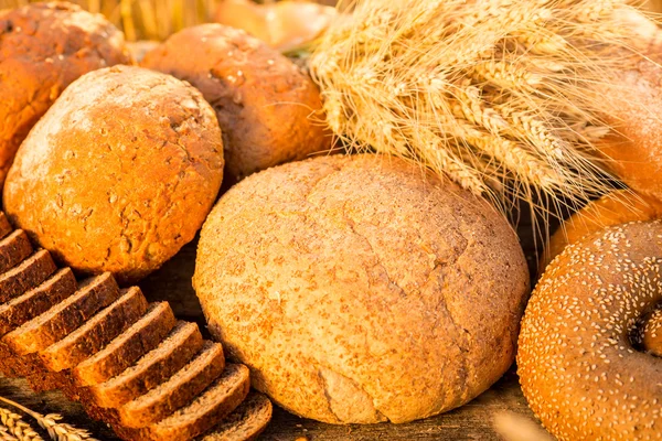 Pão e trigo na mesa de madeira — Fotografia de Stock