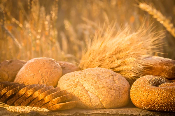 Pão e trigo na mesa de madeira — Fotografia de Stock