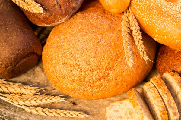 Pão caseiro e trigo na mesa de madeira — Fotografia de Stock