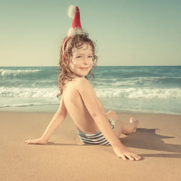 Kind mit Weihnachtsmütze am Strand — Stockfoto