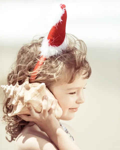 Kind mit Weihnachtsmütze am Strand — Stockfoto