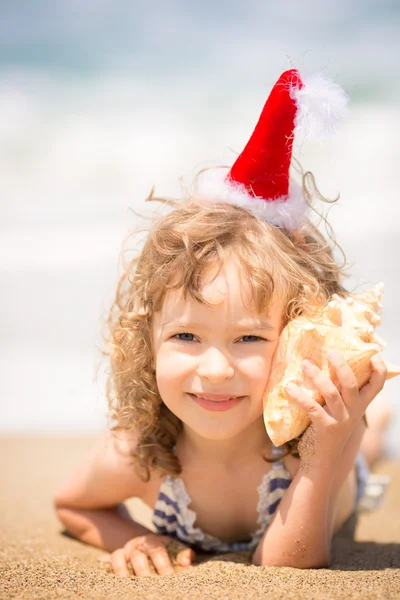 Criança em chapéu de Santa na praia — Fotografia de Stock