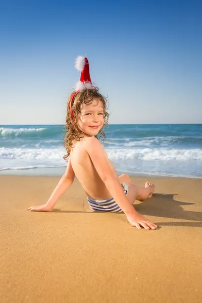 Criança em chapéu de Santa na praia — Fotografia de Stock