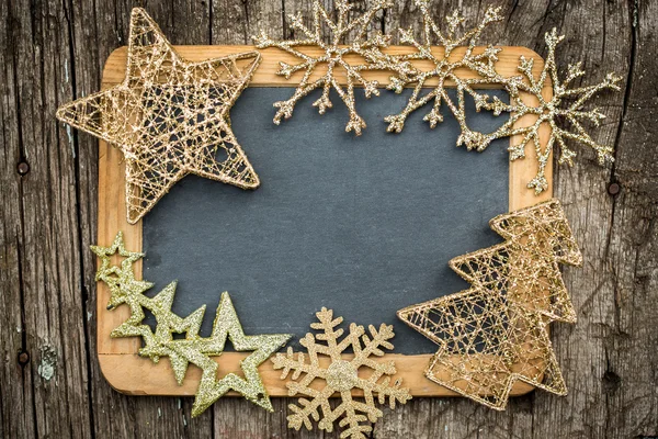 Gold Christmas tree decorations on vintage wooden blackboard — Stock Photo, Image