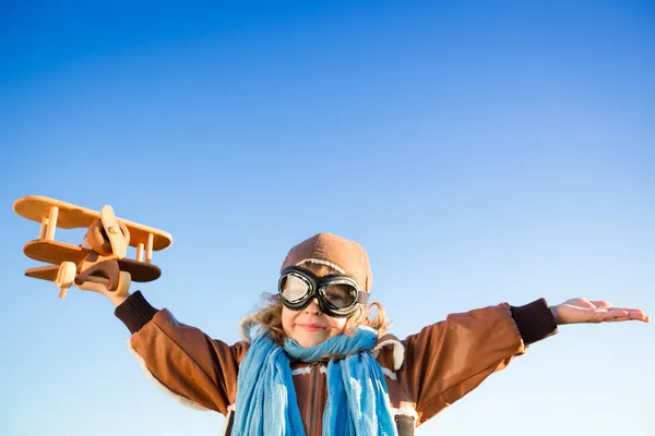 Szczęśliwe dziecko grając z samolocikiem przeciw błękitne niebo — Zdjęcie stockowe