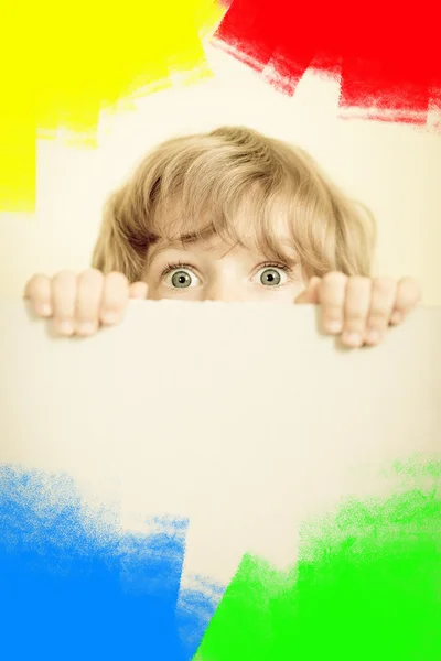 Criança olhando por trás do papel em branco — Fotografia de Stock