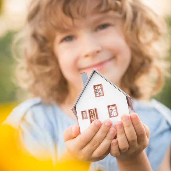 Criança segurando casa em mãos — Fotografia de Stock