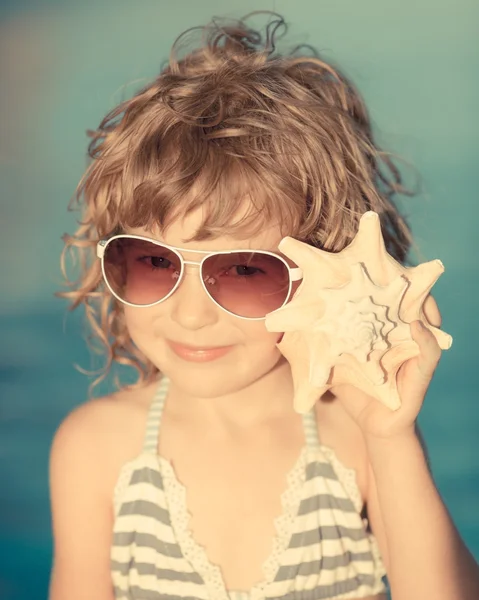 Lyckligt barn lyssna på seashell på stranden — Stockfoto