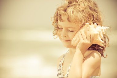 mutlu çocuk dinlemek için seashell Beach
