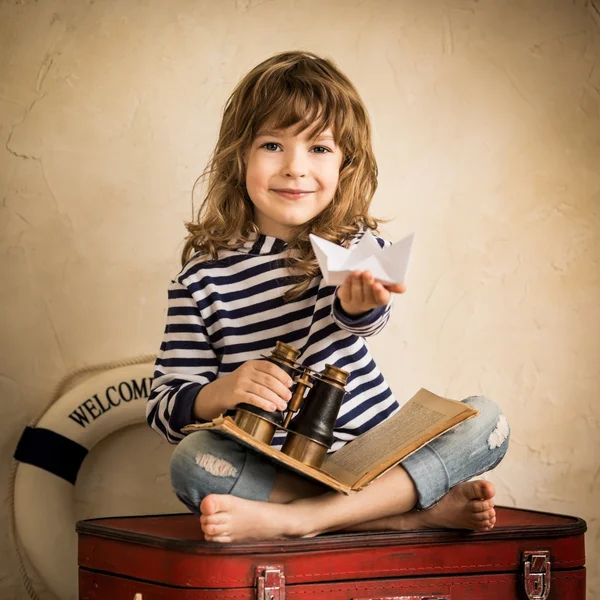 Happy kid playing with paper sailing boat indoors — Stock Photo, Image