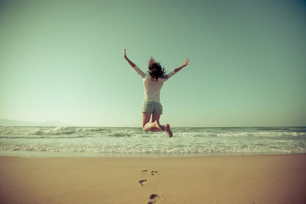 Szczęśliwa kobieta skoki na plaży — Zdjęcie stockowe