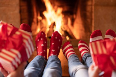 Noel çoraplı aile şöminenin yanında. Anne, baba ve çocuklar birlikte eğleniyorlar. İnsanlar evde dinleniyor. Kış tatili Xmas ve Yeni Yıl konsepti