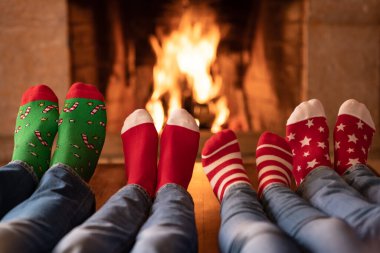 Noel çoraplı aile şöminenin yanında. Anne, baba ve çocuklar birlikte eğleniyorlar. İnsanlar evde dinleniyor. Kış tatili Xmas ve Yeni Yıl konsepti