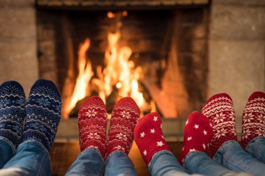 Noel çoraplı aile şöminenin yanında. Anne, baba ve çocuklar birlikte eğleniyorlar. İnsanlar evde dinleniyor. Kış tatili Xmas ve Yeni Yıl konsepti